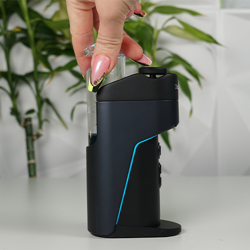 Dr. Dabber Switch Go auf einem Tisch, während eine Frau den Glas-Bubbler ansetzt