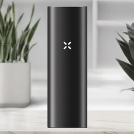 Vorderansicht des New PAX Mini Vaporizers in der Farbe Onyx mit beleuchtetem PAX Logo auf dem eleganten schwarzen Aluminiumgehäuse, platziert in einer modernen Umgebung.
